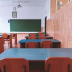 An empty classroom with rows of desks and chairs, symbolizing declining birth rates, aging populations, and shrinking student enrollment.