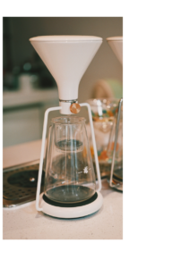 A white funnel narrowing into a glass vessel, symbolizing abundant information being filtered into scarce human attention in the AI economy.