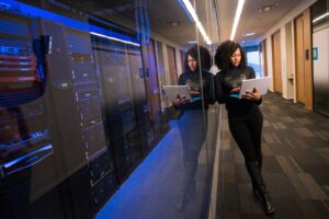 Data center professional walking beside server racks with a tablet, representing AI infrastructure and the changing workforce.