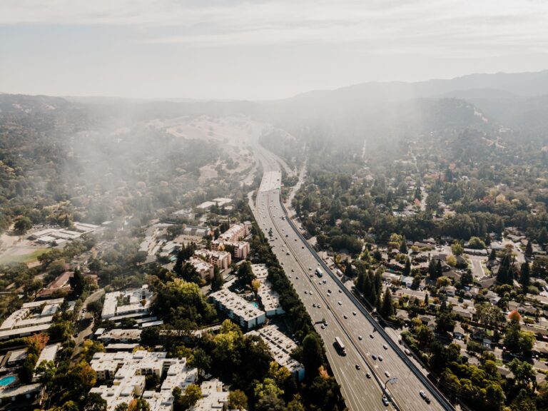 Aerial view of a California suburban community with a major highway, illustrating how climate risk and insurance availability are reshaping housing finance and mortgage markets.