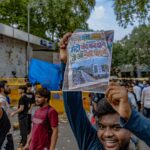 Protester at the CJP protest holds up a handwritten sign referencing the Delhi Metro shutdown during the demonstration