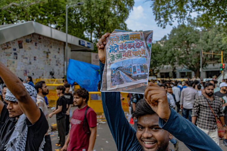 Protester at the CJP protest holds up a handwritten sign referencing the Delhi Metro shutdown during the demonstration