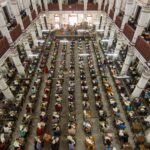 Overhead view of hundreds of students taking a competitive exam in a colonnaded heritage hall in India