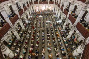 Overhead view of hundreds of students taking a competitive exam in a colonnaded heritage hall in India