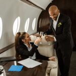 Two business executives toast with champagne inside a private jet cabin, illustrating the elite pivot toward privacy and time-saving luxuries.