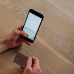 Hands holding a smartphone and credit card while entering payment details, illustrating the verification steps behind the Trust Tax