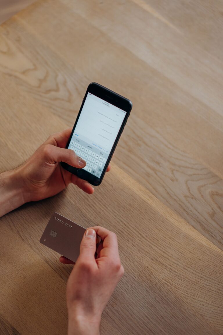 Hands holding a smartphone and credit card while entering payment details, illustrating the verification steps behind the Trust Tax