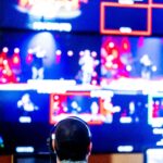 Person sitting in front of multiple glowing digital screens representing the attention economy and endless online content