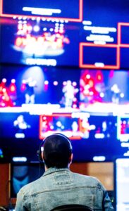 Person sitting in front of multiple glowing digital screens representing the attention economy and endless online content