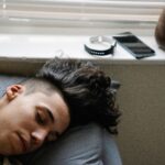 Person sleeping beside a smartphone and sleep tracking wearable
