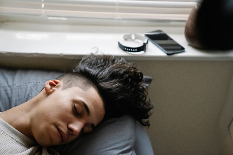 Person sleeping beside a smartphone and sleep tracking wearable