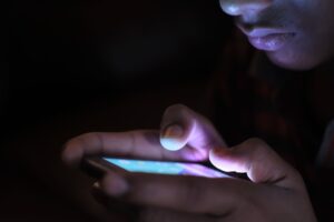 Person using a glowing smartphone in the dark, representing the rise of betting, trading and speculation apps
