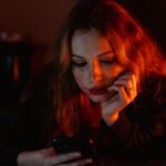 Worried woman looking at a smartphone as AI voice cloning and deepfake scams make phone calls harder to trust