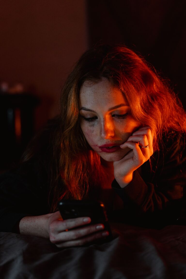 Worried woman looking at a smartphone as AI voice cloning and deepfake scams make phone calls harder to trust