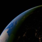 Earth seen from space at night with illuminated areas along the planet's surface