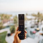 Person holding a simple feature phone against a modern city background