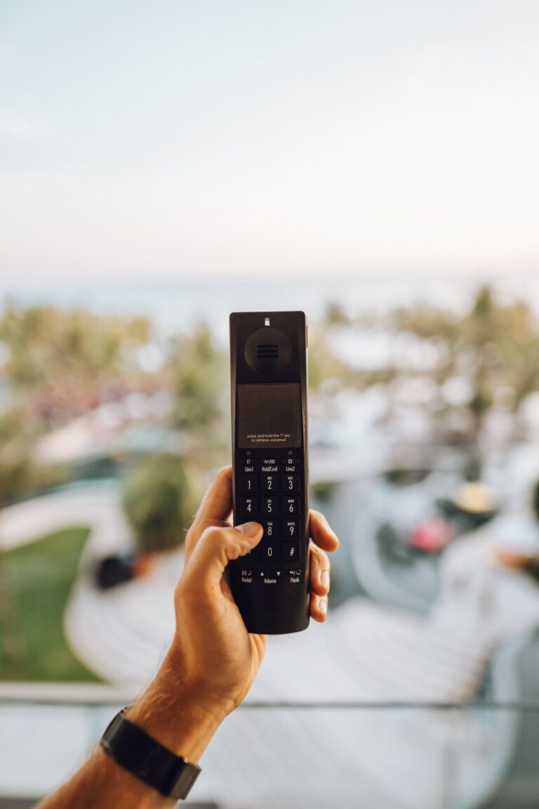 Person holding a simple feature phone against a modern city background