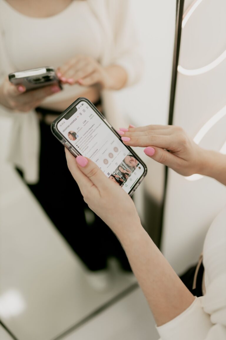 Person browsing a social media app on a smartphone while standing in front of a mirror, illustrating how algorithms influence fashion and personal identity.