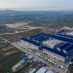 Aerial drone view of a large scam compound in Cambodia with blue-roofed buildings and perimeter security