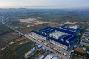 Aerial drone view of a large scam compound in Cambodia with blue-roofed buildings and perimeter security