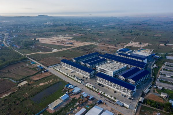 Aerial drone view of a large scam compound in Cambodia with blue-roofed buildings and perimeter security