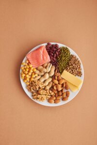 Plate showing salmon, beans, lentils, chickpeas, nuts and cheese as protein-rich foods