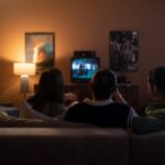 Three people watching television together in a dark living room