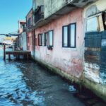 Buildings standing beside rising water in a sinking urban area