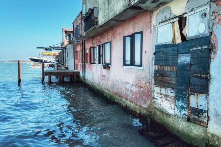 Buildings standing beside rising water in a sinking urban area