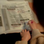 Person searching and marking job listings in a newspaper