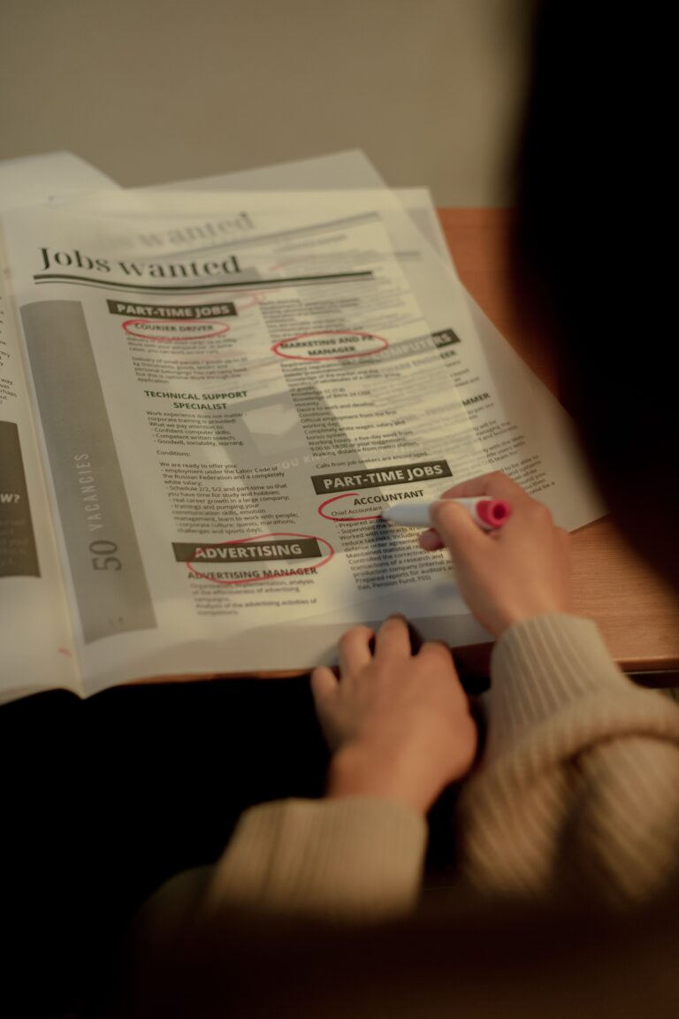 Person searching and marking job listings in a newspaper