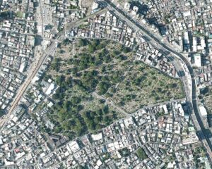 Aerial view of a large cemetery surrounded by dense urban development and major roads