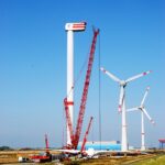 Wind turbine being dismantled during repowering as other turbines continue operating in the background