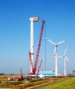 Wind turbine being dismantled during repowering as other turbines continue operating in the background