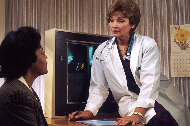 Female patient discussing medical imaging with a doctor during a clinical consultation.