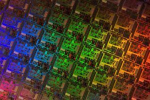 Close-up of a semiconductor die showing intricate microchip circuitry in vivid colours.
