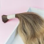 A tied bundle of human hair prepared for use in hair extensions.