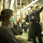 Commuter wearing over-ear headphones on a crowded train.