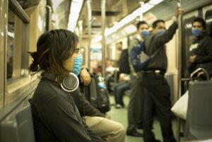 Commuter wearing over-ear headphones on a crowded train.