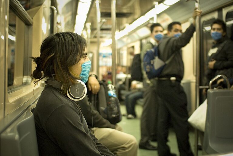 Commuter wearing over-ear headphones on a crowded train.